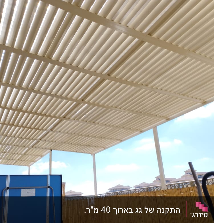 גג עץ עם קורות, גדר במבוק, שמיים בהירים